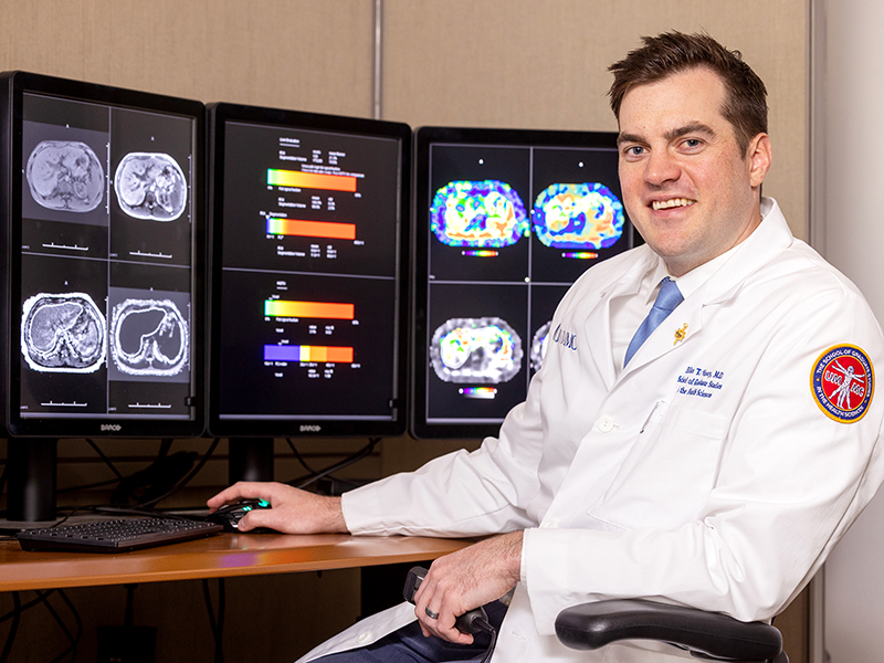 Dr. Elliot Varney sits before a patient's MRI scans that were evaluated for liver fat and liver fibrosis. The images, taken from a study he conducted, are included in his dissertation.